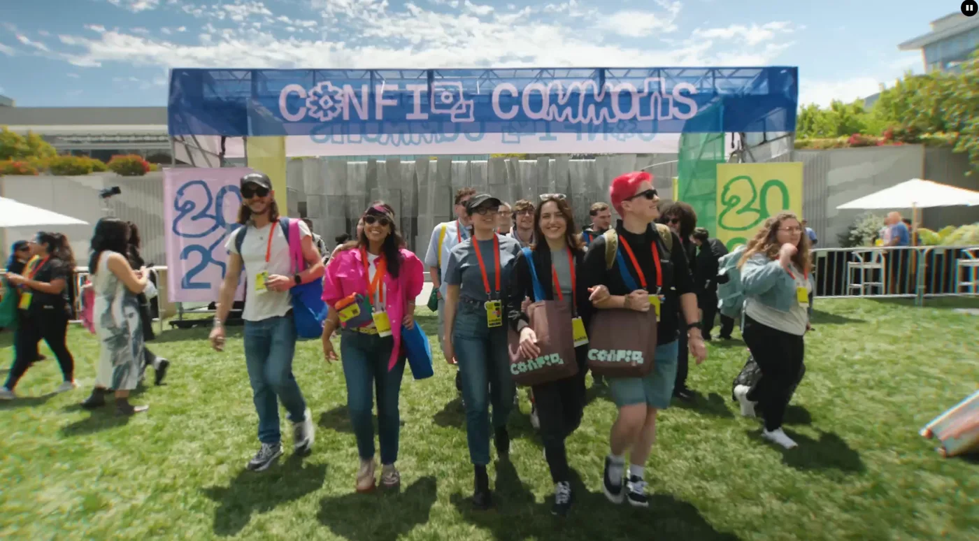 Attendees walking through Config Commons, the outdoor community space at Figma Config 2026, with colourful banners and the conference logo overhead